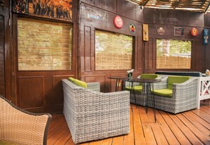 A cozy outdoor seating area with wicker furniture and a wooden deck. - Whispering Palms Gardens (Nairobi)