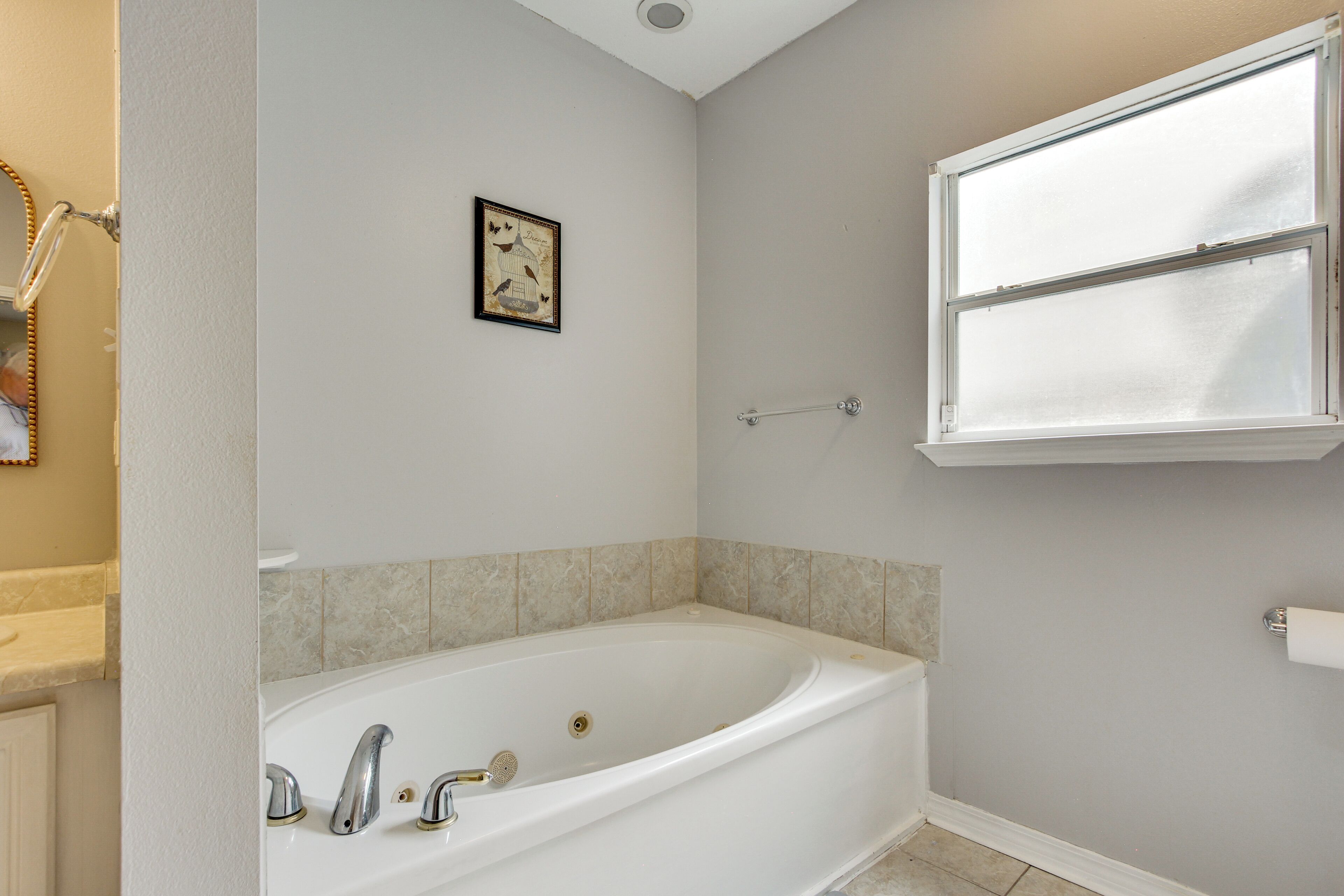 A bathroom with a freestanding bathtub, a window, and a framed picture on the wall.