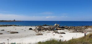 Ein Strand mit großen Felsen, blauem Himmel und dem Ozean.