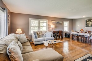 A spacious living room with a sofa, a coffee table, and a dining area with a table and chairs. - Fishing & Skiing Base! Residential Bozeman Escape (Bozeman)