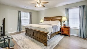 A bedroom with a wooden bed, two bedside tables with lamps, a ceiling fan, and a glass desk with a computer. - Hike, Golf, Explore: Home 10 Mi to Lake Lanier! (Buford)