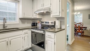 A kitchen with white cabinets, a stainless steel stove, and a window with blinds. - Hike, Golf, Explore: Home 10 Mi to Lake Lanier! (Buford)