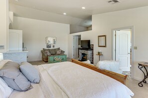 A bedroom with a large bed, a dresser, a fireplace, and a door leading to another room. - Spacious Escape Near Mesa Verde National Park! (Mancos)