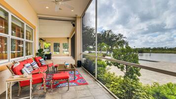 A balcony with a red sofa, a small table, and a view of a body of water.