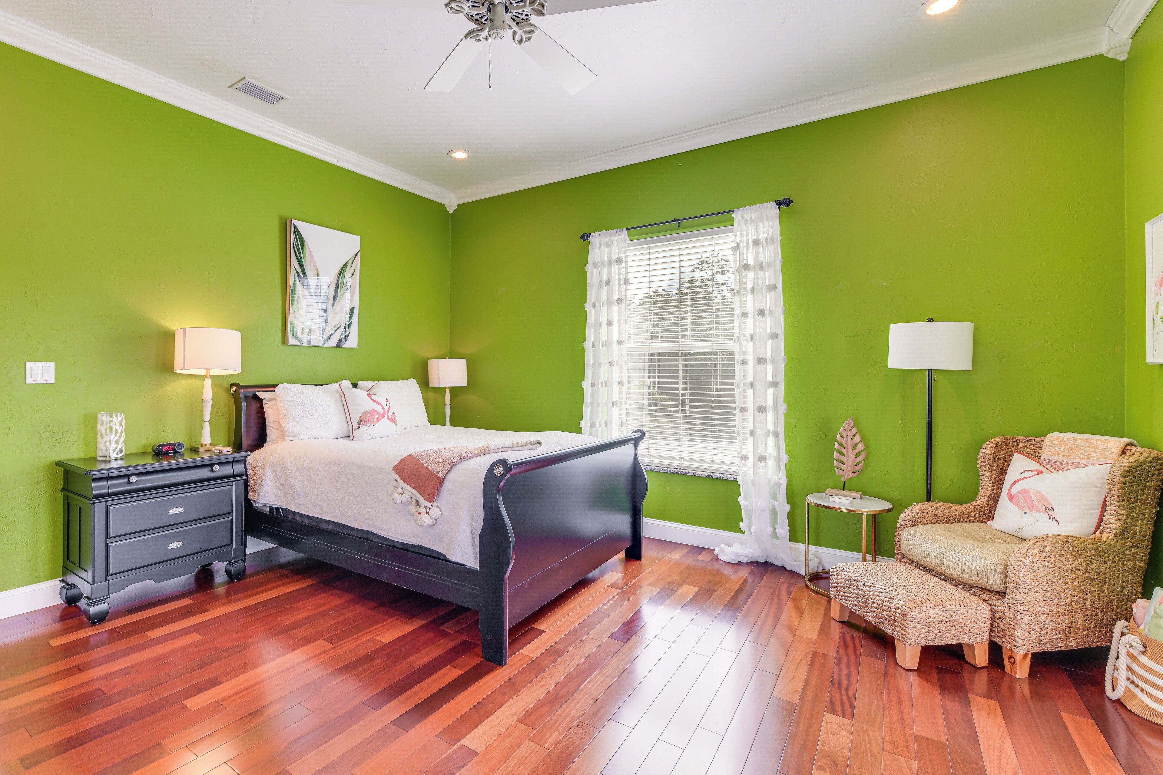 A bedroom with a bed, a nightstand, a chair, and a window with curtains.