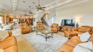 A spacious living room with leather sofas, a coffee table, and a TV. There is a staircase leading to an upper level. - Waterfront Arcadia Home w/ Dock on Peace River (Fort Ogden)