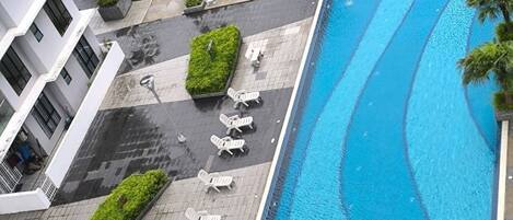 Un área de piscina en la azotea con sillones de descanso y una piscina azul cristalina.