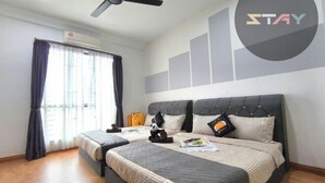 Une chambre d’hôtel avec un lit, un ventilateur de plafond, une fenêtre avec des rideaux et un mur orné d’un logo.