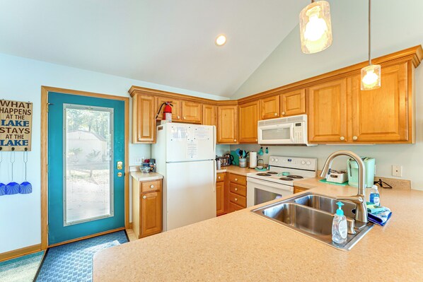 A kitchen with wooden cabinets, a refrigerator, a microwave, a stove, and a sink. - 13 Mi to South Haven: Lakefront Retreat w/ Dock! (Grand Junction)