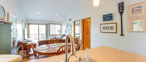A kitchen with a central island, a dining area with a table and chairs, and a view of the outdoors.