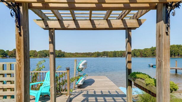 A wooden deck with a pergola, a kayak, and a paddleboard. - 13 Mi to South Haven: Lakefront Retreat w/ Dock! (Grand Junction)