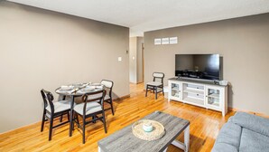 A living room with a dining table, chairs, a sofa, a TV, and a cabinet. - Walk to SC State University & Claflin: Cozy Home (Orangeburg)