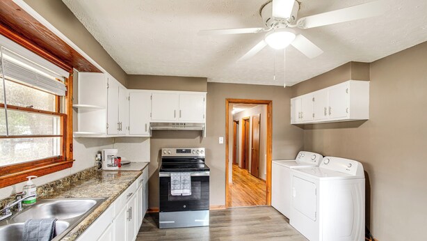 A kitchen with white cabinets, a stainless steel sink, a stove, and a ceiling fan. - Walk to SC State University & Claflin: Cozy Home (Orangeburg)