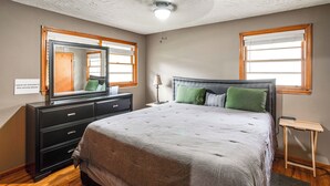 A bedroom with a large bed, a dresser, a mirror, and two windows with blinds. - Walk to SC State University & Claflin: Cozy Home (Orangeburg)