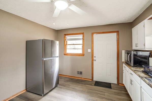 A kitchen with a stainless steel refrigerator, a microwave, and white cabinets.
