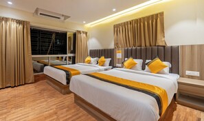 Habitación de hotel con dos camas, cortinas color beige, suelo de madera y aire acondicionado instalado en la pared.