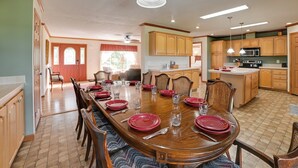 A spacious dining area with a large wooden table set for six, surrounded by wooden chairs. - Near Garden of the Gods: Home w/ Fire Pit, Hot Tub (Elizabethtown)