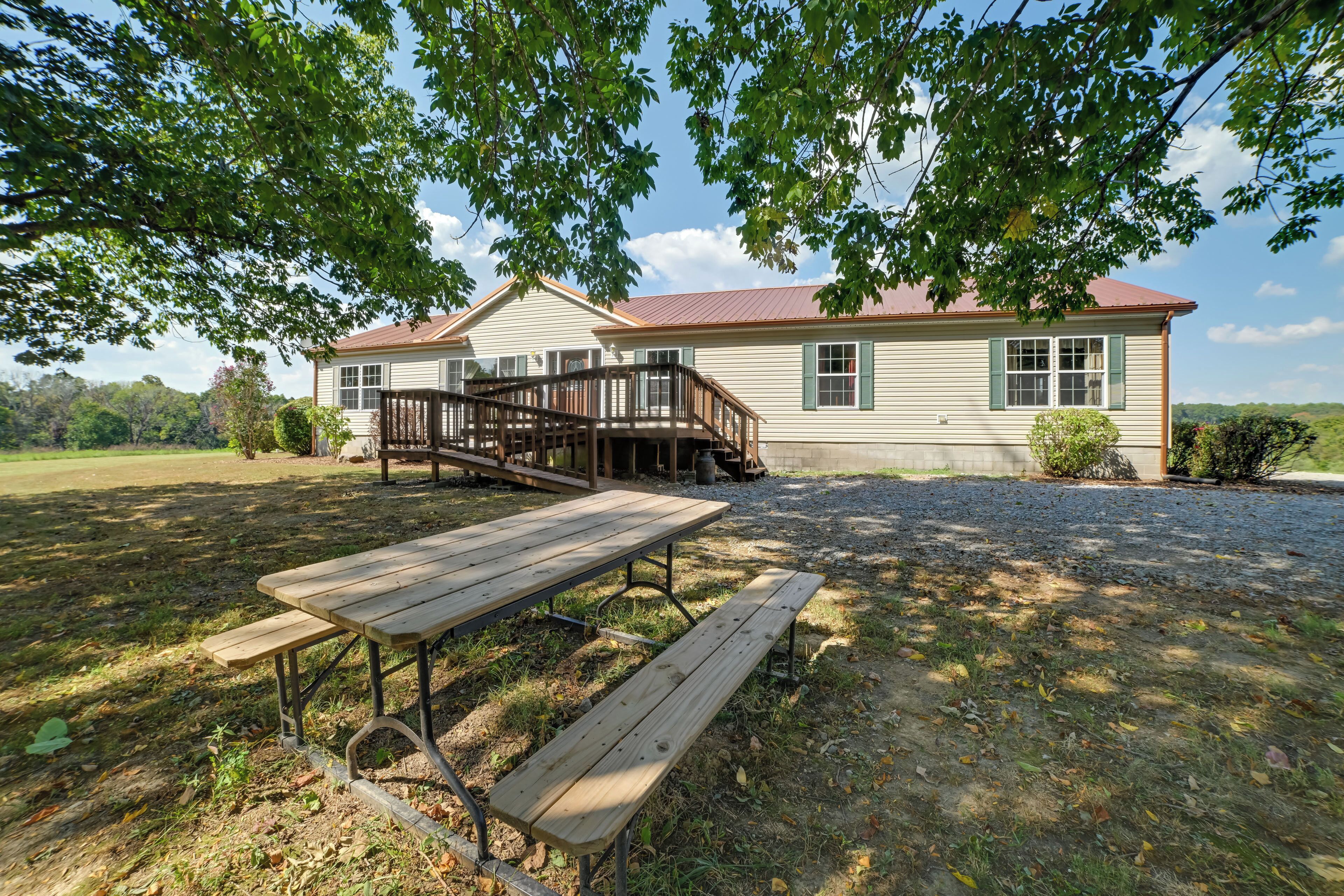 A house with a wooden deck and a picnic table in front.