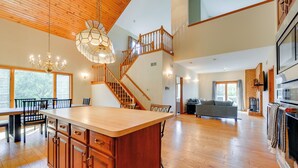 A spacious kitchen with a wooden island, a dining area with a table and chairs, a staircase leading to an upper level, and a large window providing natural light. - 3 Mi to Prettyboy Reservoir! Maryland Hideaway (Freeland)
