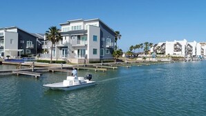 A waterfront property with modern buildings, a dock, and a boat. - Las Velas Village Luxury with a view (South Padre Island)