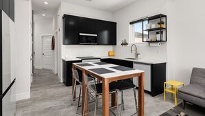 A compact kitchen with black cabinets, a white countertop, and a small dining area with a wooden table and chairs. - Las Velas Village Luxury with a view (South Padre Island)