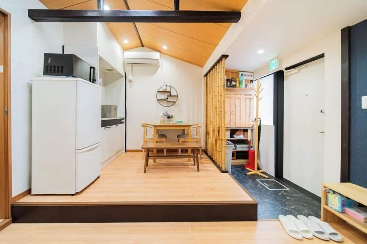 A compact kitchen with a refrigerator, a dining table, and a small seating area.