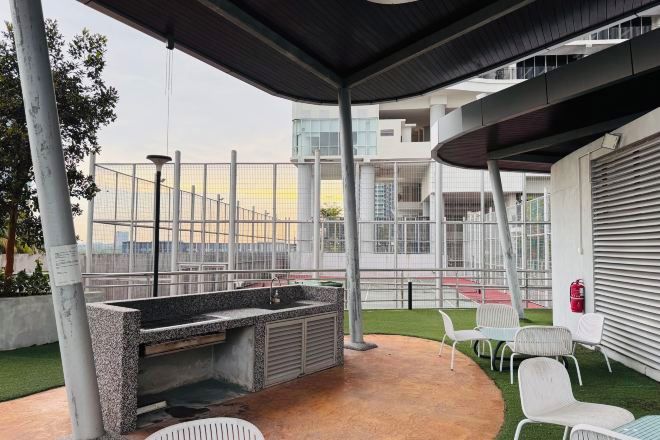An outdoor patio with a stone sink, white chairs, and a view of a modern building.