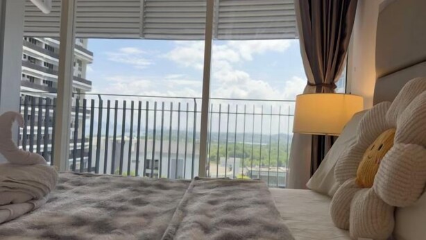 A hotel room with a bed, a lamp, a view of a cityscape, and a balcony with a railing. - Encorp Marina Residences Puteri Habour (Iskandar Puteri)