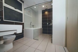 Une salle de bain moderne avec des toilettes, une douche à parois de verre et un mur recouvert de carreaux noirs.