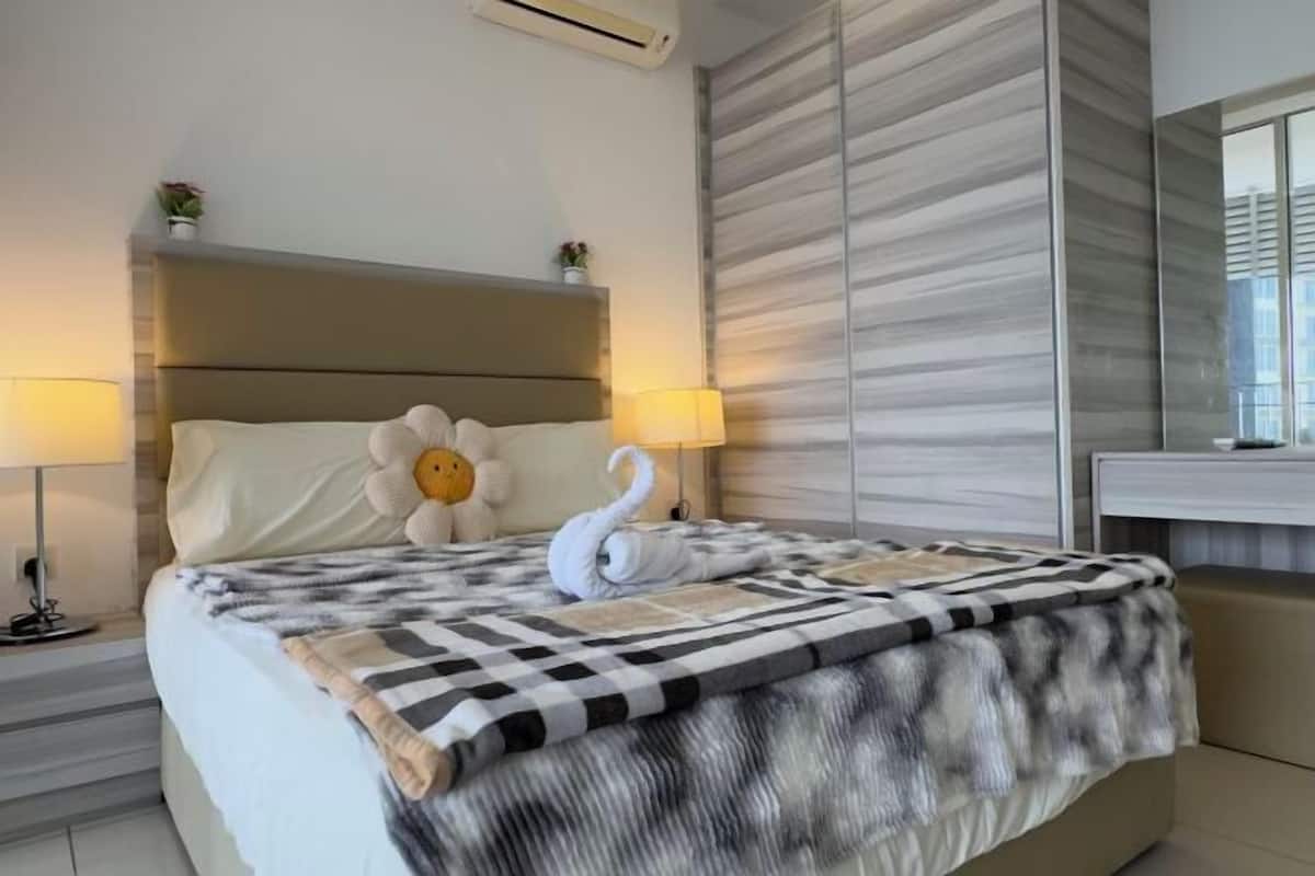 Une chambre d’hôtel avec un lit, deux lampes de chevet, une tête de lit, un mur à motifs rayés et un miroir.