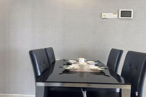 Une table de conférence avec quatre chaises, une tasse blanche et un petit appareil électronique fixé au mur.
