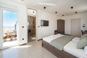 A modern bedroom with a bed, a wooden wardrobe, a bathroom with a shower, and a view of the sea through a glass door. - The old man and the sea Inn-Double room with balcony and Sea view (Novalja)