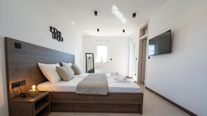 A modern bedroom with a wooden headboard, a flat-screen TV mounted on the wall, and a bedside table with a lamp. - The old man and the sea Inn-Double room with balcony and Sea view (Novalja)