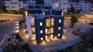 A modern multi-story building with balconies and a paved area in front. - The old man and the sea Inn-Double room with balcony and Sea view (Novalja)