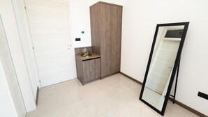 A room with a white door, a wooden wardrobe, a small cabinet with a mirror, and a large mirror leaning against the wall. - The old man and the sea Inn-Double room with balcony and Sea view (Novalja)
