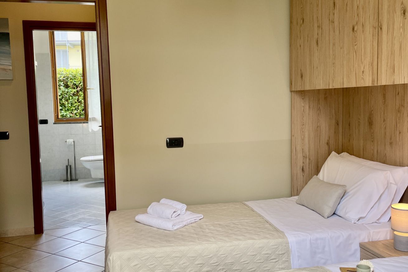 Una habitación de hotel con una cama, cabecero de madera y vistas al baño a través de una puerta abierta.