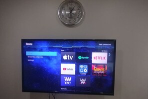 A flat-screen TV mounted on a wall with a clock above it. - Aveline Suites II, Garden/City view,2br, amenities (Mandaluyong)