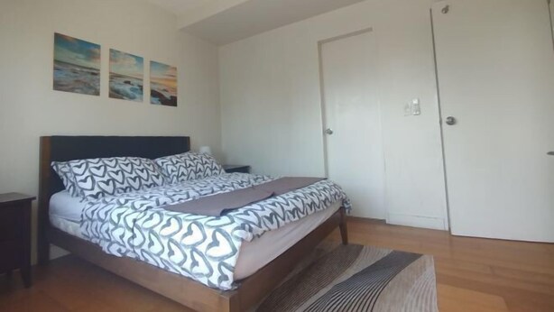 Um quarto com uma cama, uma mesa de cabeceira, uma porta e um quadro na parede.
