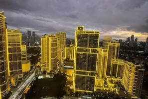 A cityscape with illuminated high-rise buildings, a bridge, and a cloudy sky. - Aveline Suites II, Garden/City view,2br, amenities (Mandaluyong)