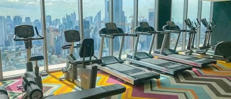 Ein Fitnessstudio mit Laufbändern, Kraftgeräten und einem farbenfrohen, Zickzack-Muster-Boden.