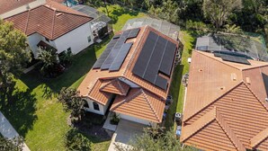 Un quartier résidentiel composé de plusieurs maisons, chacune dotée d’un toit recouvert de tuiles rouges et de panneaux solaires.