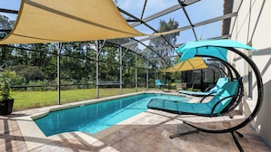 Une piscine dotée de chaises longues et d’une structure en forme de pergola.