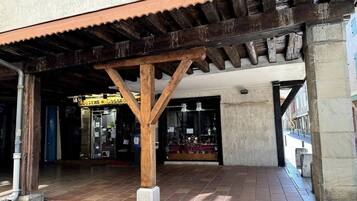A covered outdoor area with a wooden structure, a tiled floor, and a shop with glass display windows.