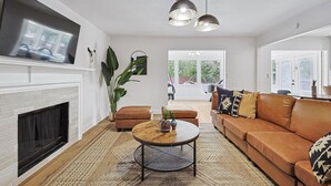 A modern living room with a fireplace, leather sofa, round coffee table, and pendant lighting.