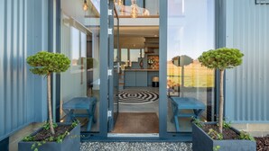 A modern building entrance with glass doors, a central circular rug, and two potted trees. - Indigo Barn, Warham, Norfolk (Warham)