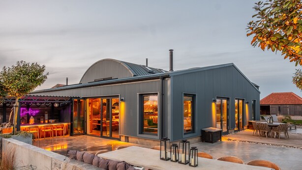 A modern building with a covered outdoor seating area, large windows, and a patio with tables and chairs. - Indigo Barn, Warham, Norfolk (Warham)