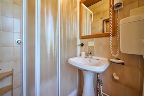 A bathroom with a white sink, a mirror, and a hairdryer on the wall. - Room 'Santa Lorica - Camera 12' with Shared Pool, Shared Garden and Wi-Fi (Sassetta)