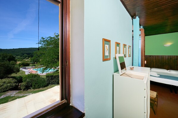 A room with a large window, a bed, a desk, and framed pictures on the wall. - Room 'Santa Lorica - Camera 12' with Shared Pool, Shared Garden and Wi-Fi (Sassetta)