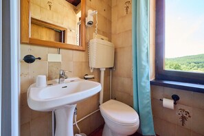 A bathroom with a sink, toilet, and window with a view of greenery. - Room 'Santa Lorica - Camera 12' with Shared Pool, Shared Garden and Wi-Fi (Sassetta)