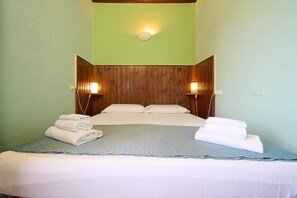 A neatly made bed with pillows and folded towels, a wooden headboard, and two wall-mounted lamps. - Room 'Santa Lorica - Camera 12' with Shared Pool, Shared Garden and Wi-Fi (Sassetta)